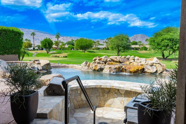 view of swimming pool featuring a lawn, a mountain view, and exterior kitchen