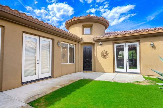 entrance to property with french doors and a lawn