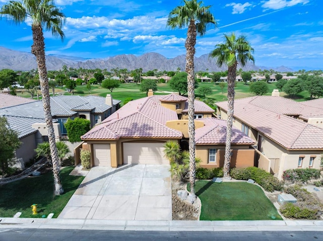 view of front facade with a garage, a front yard, and a mountain view