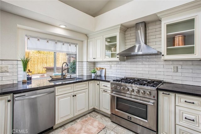 kitchen featuring appliances with stainless steel finishes, decorative backsplash, vaulted ceiling, wall chimney exhaust hood, and sink