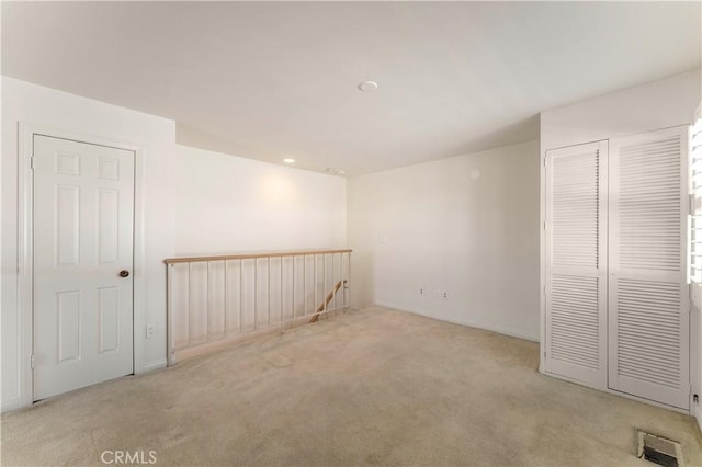 unfurnished room with carpet floors, visible vents, and baseboards