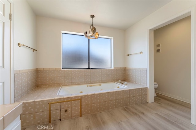 bathroom featuring hardwood / wood-style flooring, toilet, a chandelier, and tiled bath