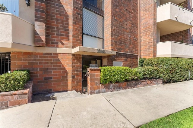 view of exterior entry featuring brick siding