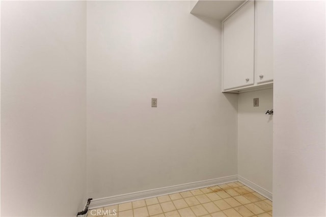 laundry room with cabinet space, baseboards, and light tile patterned floors