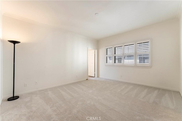 empty room with baseboards, crown molding, and carpet