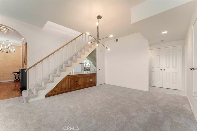 interior space featuring arched walkways, visible vents, carpet, a chandelier, and stairway