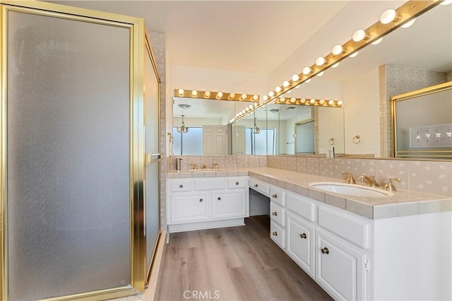 full bathroom with a sink, double vanity, decorative backsplash, wood finished floors, and a shower stall
