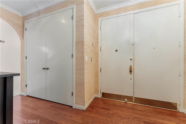 hallway with arched walkways, wood finished floors, visible vents, and crown molding