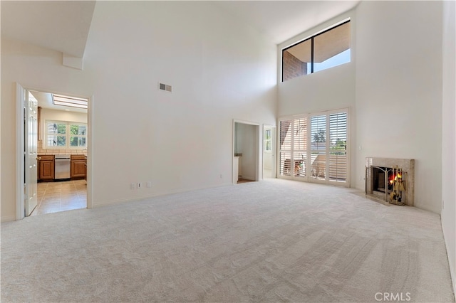 unfurnished living room featuring a high ceiling and light colored carpet