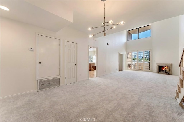 unfurnished living room with a towering ceiling, visible vents, carpet, and a lit fireplace