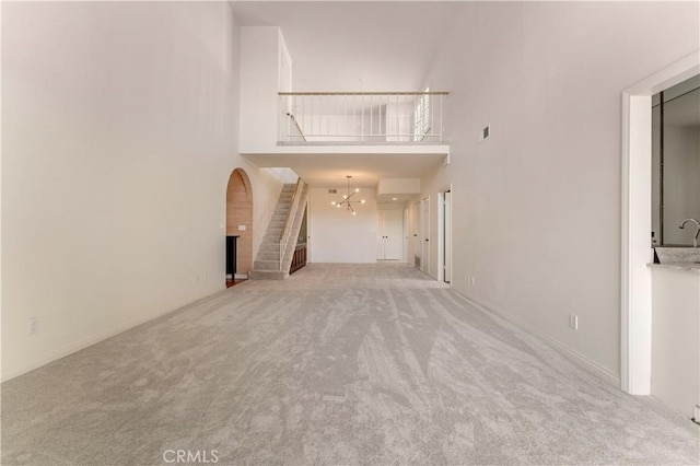 unfurnished living room with an inviting chandelier, a towering ceiling, visible vents, and carpet