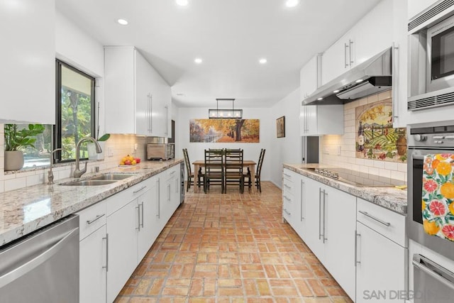 kitchen with light stone countertops, sink, white cabinetry, appliances with stainless steel finishes, and backsplash