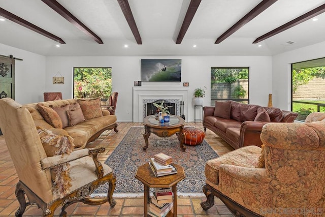 living room featuring a barn door, beam ceiling, and a wealth of natural light