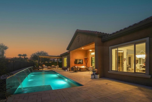 pool at dusk with pool water feature, a patio, and an outdoor hangout area