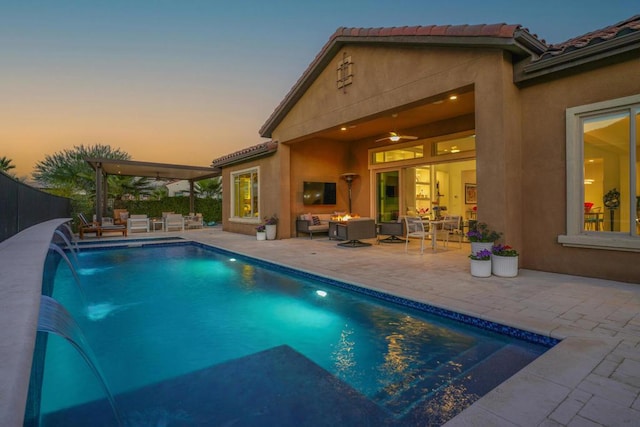 pool at dusk with pool water feature, a patio, and an outdoor living space