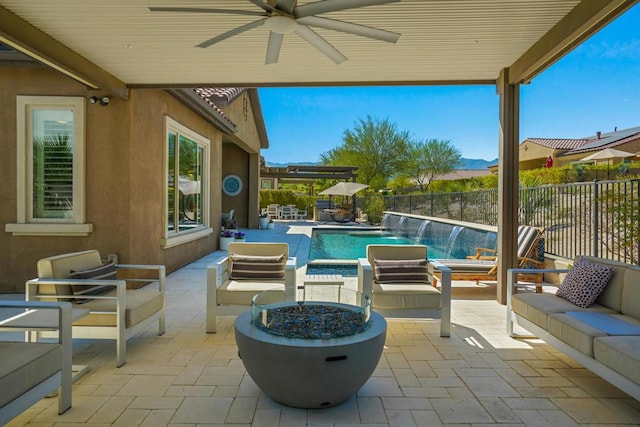 view of swimming pool with pool water feature, ceiling fan, an outdoor living space with a fire pit, and a patio