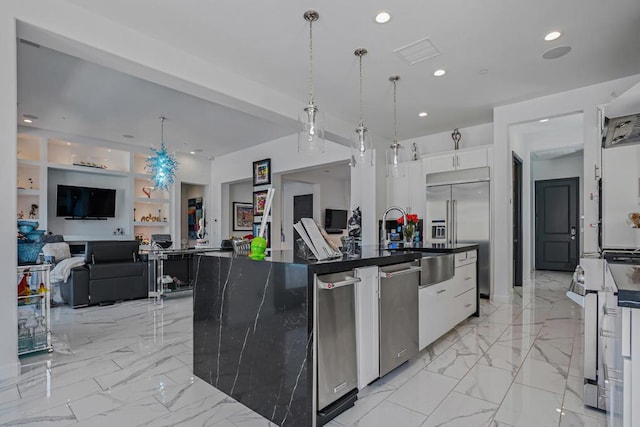 kitchen with stainless steel appliances, built in features, pendant lighting, a kitchen island with sink, and white cabinets