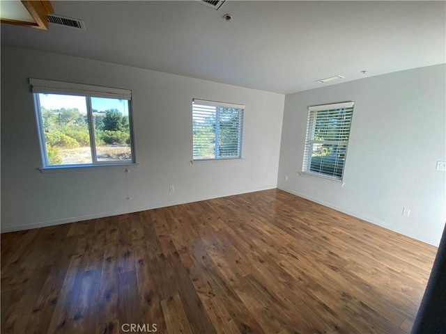 spare room with hardwood / wood-style floors and plenty of natural light