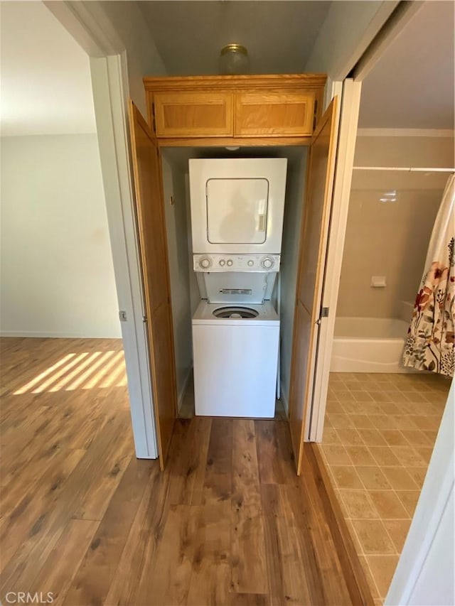 laundry room featuring stacked washer / dryer and hardwood / wood-style flooring