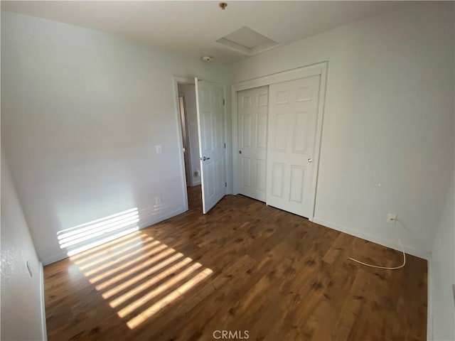 unfurnished bedroom with dark hardwood / wood-style flooring and a closet