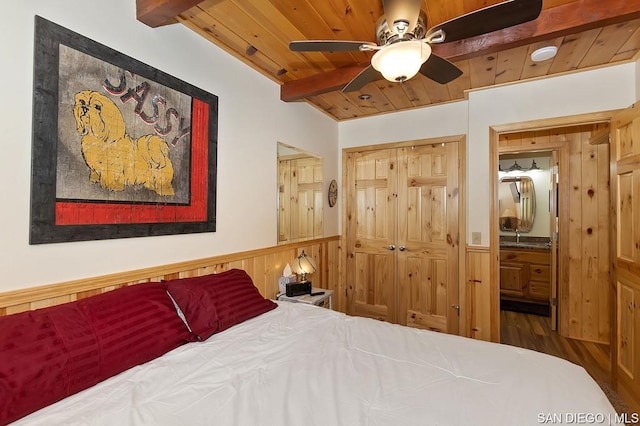 bedroom featuring connected bathroom, wooden ceiling, and beam ceiling