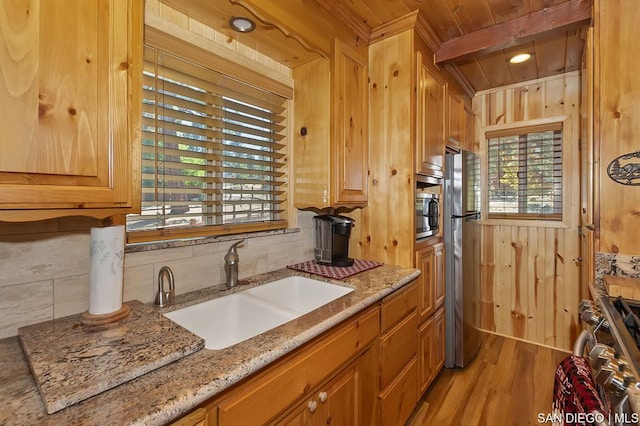 kitchen with sink, wood ceiling, wooden walls, stainless steel appliances, and decorative backsplash