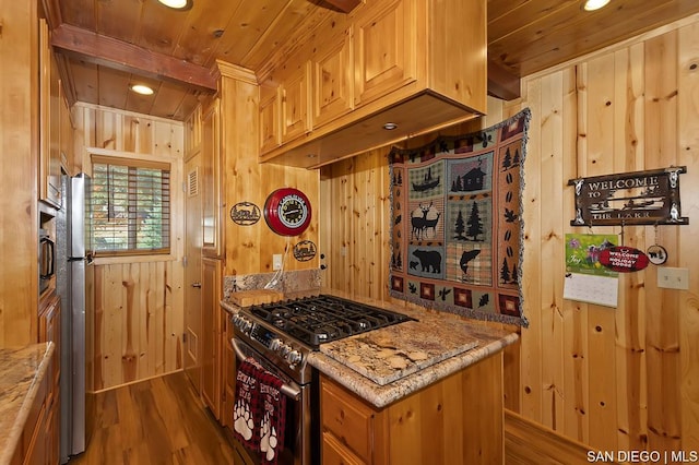 kitchen featuring appliances with stainless steel finishes, light brown cabinetry, wooden walls, hardwood / wood-style flooring, and wooden ceiling