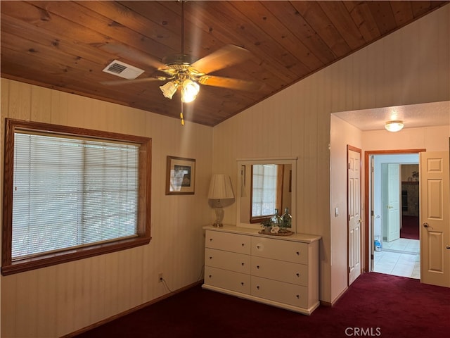 unfurnished bedroom featuring lofted ceiling, ceiling fan, dark colored carpet, wooden ceiling, and wood walls