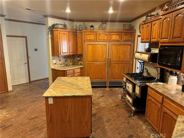 kitchen with a kitchen island, light stone countertops, tasteful backsplash, crown molding, and range with gas cooktop