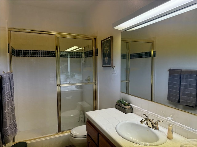 bathroom featuring an enclosed shower, vanity, toilet, and tasteful backsplash