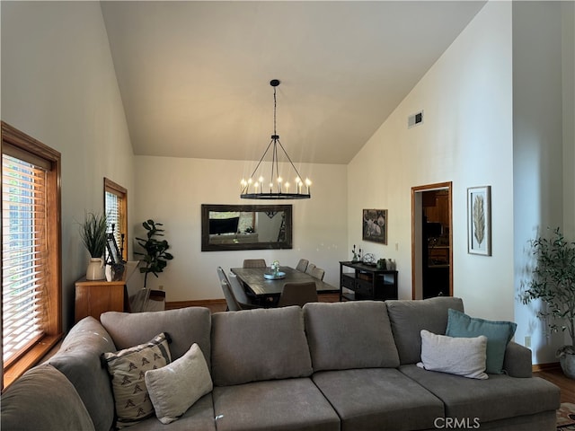 living room with high vaulted ceiling, an inviting chandelier, and wood-type flooring