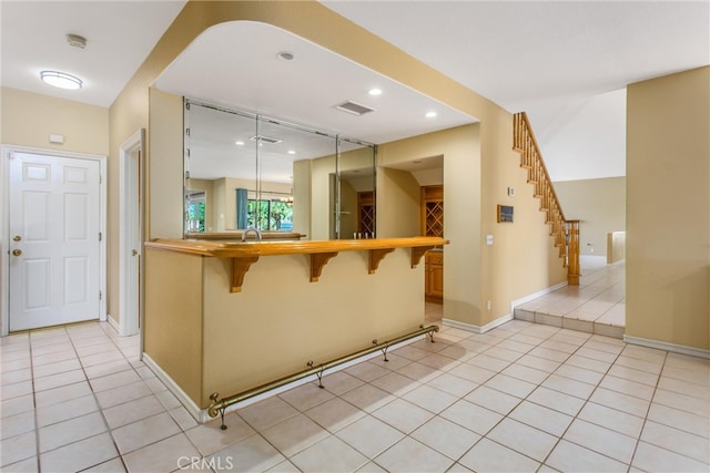 kitchen with light tile patterned floors, a kitchen bar, and kitchen peninsula