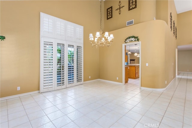 tiled spare room featuring a high ceiling and an inviting chandelier