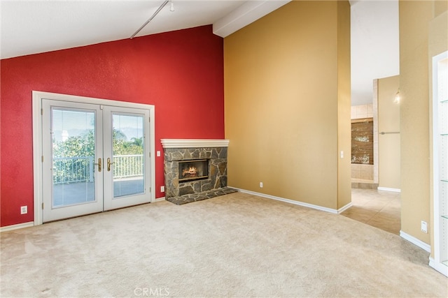 unfurnished living room featuring light carpet, a stone fireplace, lofted ceiling, and french doors