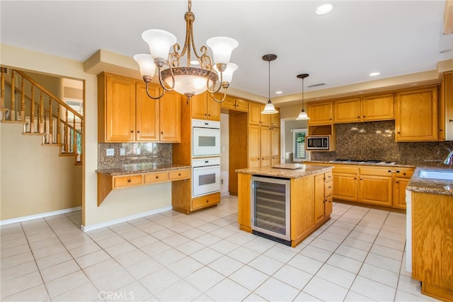 kitchen featuring pendant lighting, beverage cooler, double oven, a center island, and stainless steel microwave