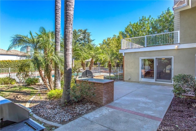 view of patio with a balcony and exterior kitchen