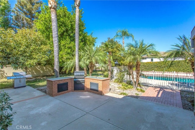 view of patio with an outdoor kitchen, a fenced in pool, and a grill