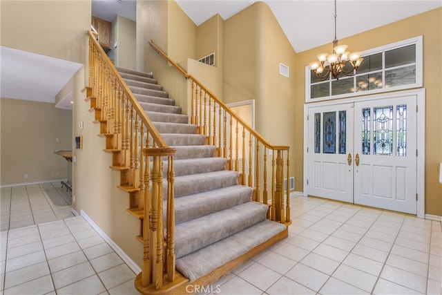 tiled entrance foyer with french doors, high vaulted ceiling, and a chandelier