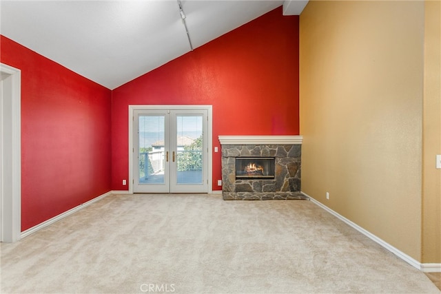 unfurnished living room with french doors, lofted ceiling, a fireplace, and carpet flooring