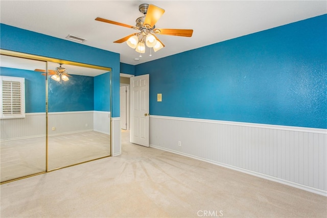 unfurnished bedroom with a closet, light colored carpet, and ceiling fan