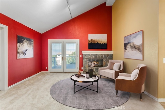 sitting room with french doors, a stone fireplace, carpet floors, and lofted ceiling