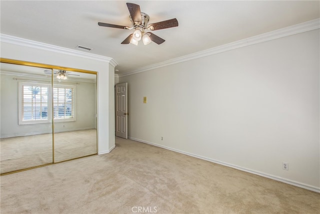 unfurnished bedroom with light carpet, a closet, and crown molding