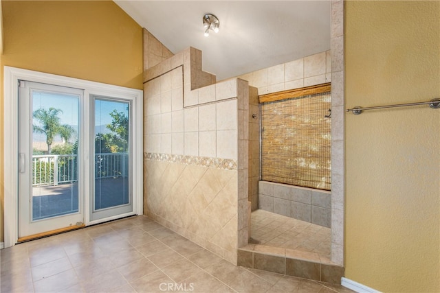 bathroom featuring tile patterned flooring, a tile shower, and high vaulted ceiling