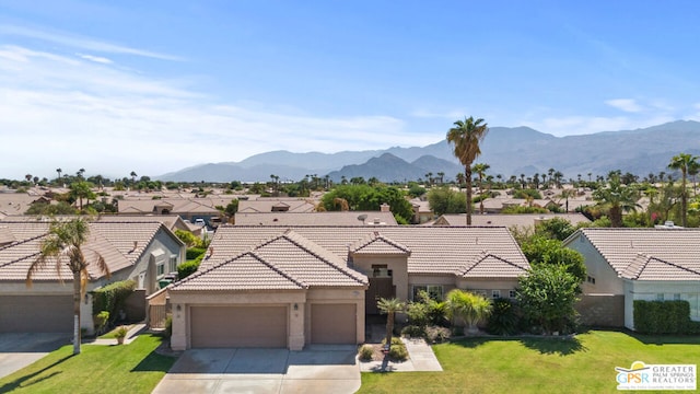 ranch-style home featuring a garage, a front yard, and a mountain view