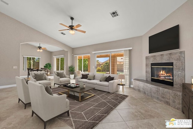 tiled living room featuring ceiling fan, a tile fireplace, a wealth of natural light, and vaulted ceiling