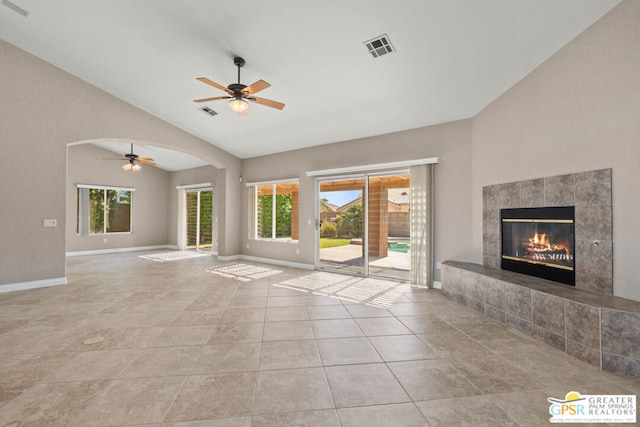 unfurnished living room with light tile patterned flooring, a tile fireplace, a wealth of natural light, and vaulted ceiling