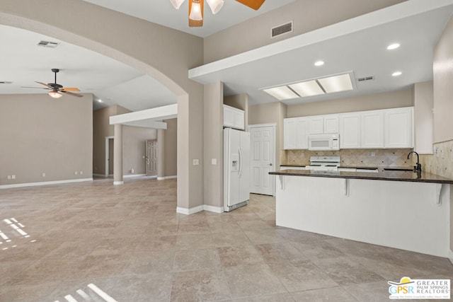 kitchen with white appliances, kitchen peninsula, white cabinetry, vaulted ceiling, and backsplash