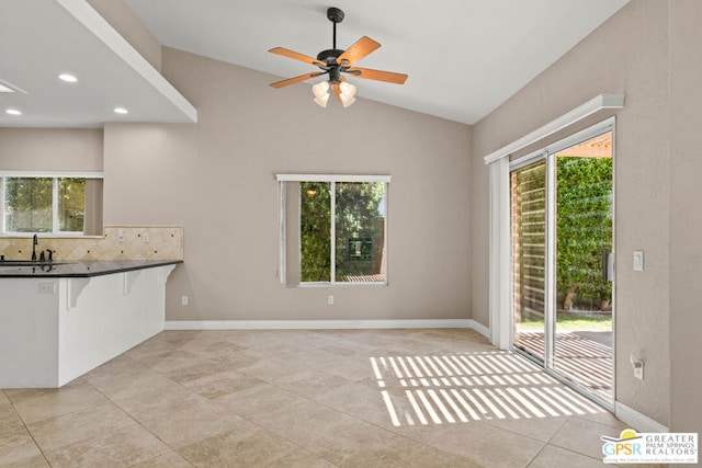 interior space featuring ceiling fan, light tile patterned flooring, lofted ceiling, and a healthy amount of sunlight