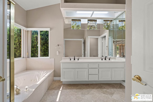 bathroom featuring tile patterned floors, a tub to relax in, vaulted ceiling, and vanity