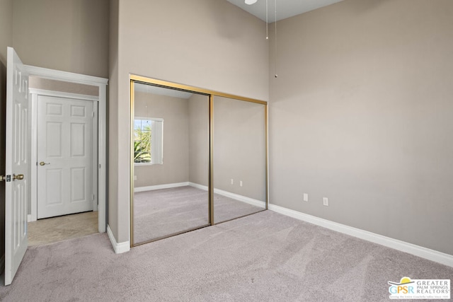 unfurnished bedroom featuring light carpet and a closet